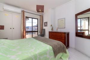 een slaapkamer met een bed, een ladekast en een spiegel bij Beco Da Hortinha in Ferragudo