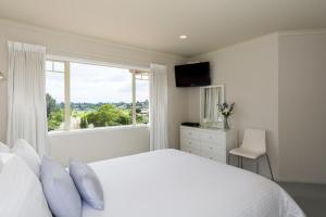 a white bedroom with a large bed and a window at Seascape Villa B&B in Tauranga