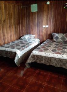 Duas camas num quarto com paredes de madeira em Hostal y cabañas los Juanes em Jardín