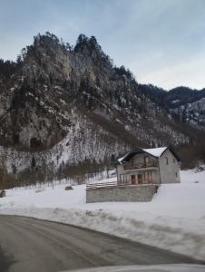 a building in the snow next to a mountain at Apartmani Tara i Zabojsko Dobrilovina in Mojkovac