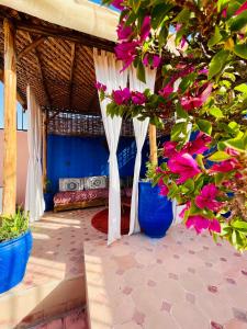 un porche con flores rosas en jarrones azules en Riad Dar Lilas, en Marrakech