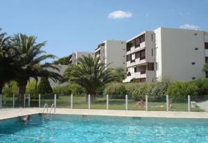 uma piscina com pessoas na água e nos edifícios em Superbe appartement piscine, tennis, vue mer et décoré avec goût em Cassis