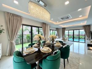 a dining room with a table and green chairs at Southern Peak Pool Villa Huay Yai Pattaya in Ban Huai Yai
