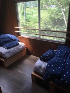 two twin beds in a room with a window at Codona Hütte in Minami Aso