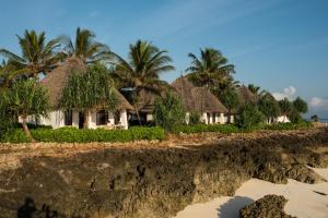 a row of houses on a beach with palm trees at Essque Zalu Zanzibar in Nungwi