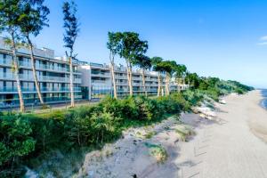 a building on the beach next to the ocean at Resort Hevenia Rewal 7 in Rewal