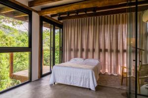 um quarto com uma cama e uma grande janela em Casa Waimea em Ubatuba