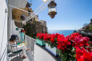 una donna seduta su un balcone con fiori rossi di Casa Carmela a Positano