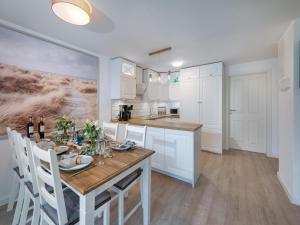 eine Küche mit einem Holztisch und weißen Schränken in der Unterkunft Ferienwohnung Flensburg in Flensburg