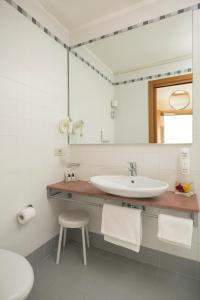 a bathroom with a sink and a mirror and a stool at Hotel Imperia in Lido di Jesolo