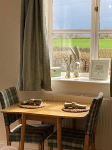 a wooden table with two chairs in front of a window at Norbin Farm in Box