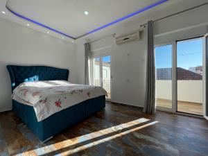 a bedroom with a blue bed in a room with windows at Apartmani centar ulcinj in Ulcinj