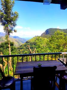 una mesa de madera en un balcón con vistas a las montañas en Rock Paradise Homestay, en Ella