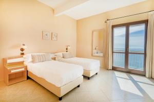 two beds in a room with a view of the ocean at Hotel La Baja in Santa Caterina