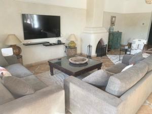 a living room with a couch and a table and a tv at Villa Mezouza in Marrakesh