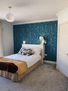 um quarto com uma cama com uma parede azul em The Milltown Apartment em Dublin