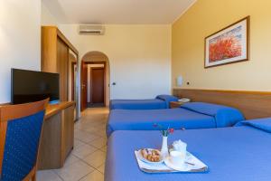 a hotel room with two beds and a tv at Hotel Relax in Syracuse