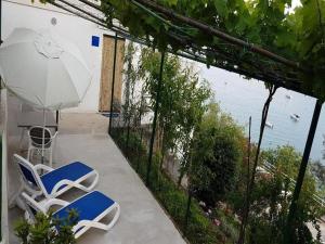 un patio con 2 sillas, una sombrilla y una mesa en Apartment By the Sea, en Rabac