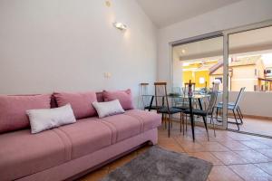 ein Wohnzimmer mit einem rosa Sofa und einem Tisch in der Unterkunft House Suzana in Banjole