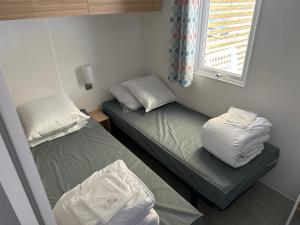 a small room with two beds and a window at mobil home 6 places tout confort in Saint-Georges-de-Didonne