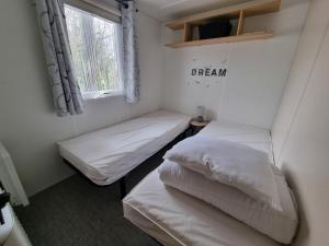 two beds in a small room with a window at Beau Mobil home 64 in Saint-Jean-de-Monts