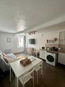 a living room with a white table and a kitchen at Appartement cocooning in Saorge