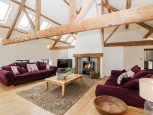 ein Wohnzimmer mit zwei lila Sofas und einem Kamin in der Unterkunft Owl Barn in Leominster