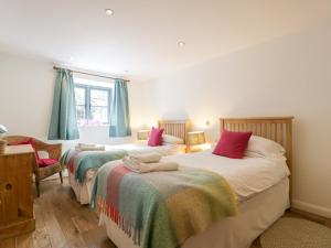 a bedroom with two beds and a chair at Owl Barn in Leominster