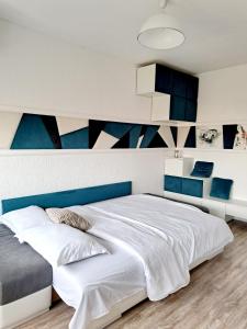 ein Schlafzimmer mit einem großen weißen Bett mit blauen Akzenten in der Unterkunft Garsonieră modernă-Zona Micalaca in Arad