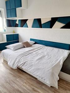 ein Schlafzimmer mit einem weißen Bett und einer blauen Wand in der Unterkunft Garsonieră modernă-Zona Micalaca in Arad