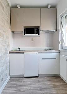 eine Küche mit weißen Schränken und einer Mikrowelle in der Unterkunft Garsonieră modernă-Zona Micalaca in Arad