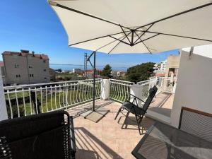- un balcon avec un parasol blanc et 2 chaises dans l'établissement Apartments Toni, à Podstrana