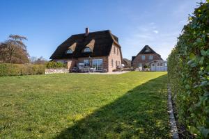 a large brick house with a thatched roof at Reetdachhaus Ahoi Reetdachhaus Ahoi in Tating