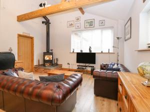 a living room with leather furniture and a fireplace at Primose Cottage in Cromer