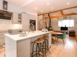 a kitchen and living room with a counter and stools at Primose Cottage in Cromer
