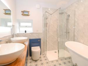 une salle de bain avec deux lavabos et une douche en verre dans l'établissement Primose Cottage, à Cromer 13 autres photos
