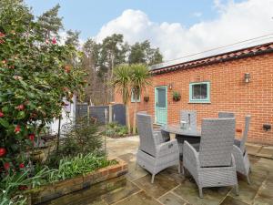 a patio with a table and chairs in a garden at Primose Cottage in Cromer