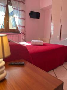 ein Schlafzimmer mit einem roten Bett und einem Tisch mit Fernbedienung in der Unterkunft Sweet House in Agerola