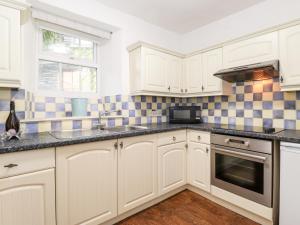a kitchen with white cabinets and a sink and a microwave at Meadow Cottage in Kendal