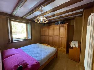 ein Schlafzimmer mit einem lila Bett und einem Fenster in der Unterkunft Santi’s Apartment in Folgaria