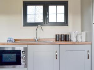 a kitchen with a sink and a microwave at Checkers Cottage - Beaufort Estate in Belladrum