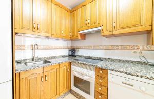 een keuken met houten kasten, een wastafel en een vaatwasser bij Casa Morana Apartamento con garaje in Zamora