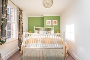 a white crib in a room with green walls at Flat 2 Peter Lane Cosy 1-Bed Flat in the Heart of York City Centre Pass the Keys in York