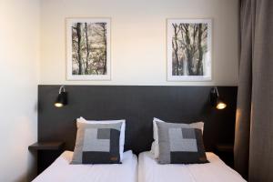 a bedroom with two beds and two pictures on the wall at Hotel Bishops Arms Mora in Mora
