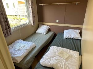 2 camas en una habitación pequeña con ventana en Mobilhome 6 personnes, en Saint-Georges-de-Didonne