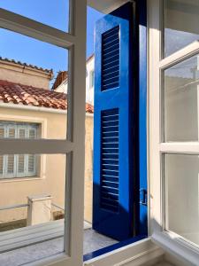 a blue door is seen through a window at Camara’s Gem in Poros