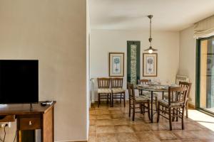 comedor con mesa, sillas y TV en Family villa in Torremirona Resort, en Navata