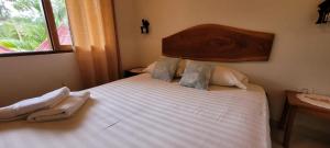 um quarto com uma grande cama branca e uma cabeceira em madeira em Rústico & Hotel Boutique Las Churapas em San José de Chiquitos