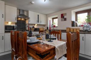 cocina con mesa de madera con sillas y comedor en The Coach House, en Penmachno
