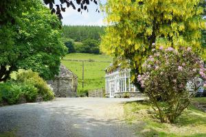 a house in the middle of a road with flowers at The Coach House in Penmachno